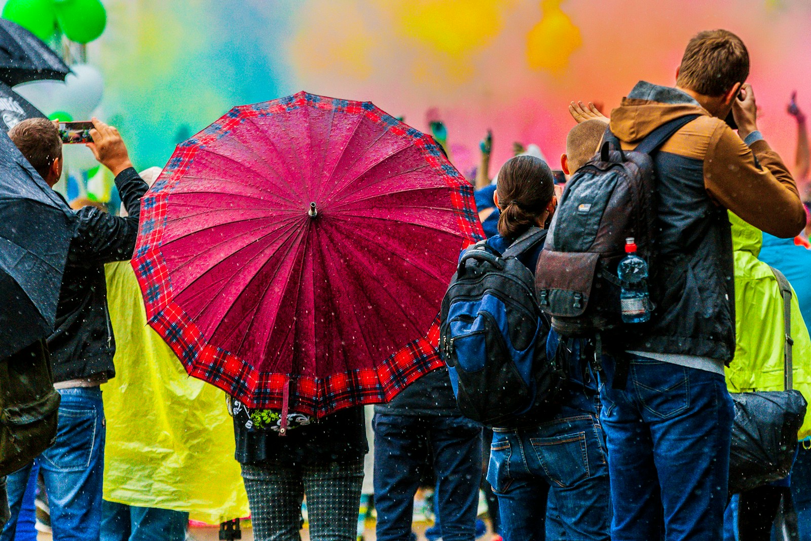 Crowd of dark umbrellas with one red umbrella standing out